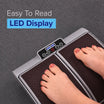 Person using a vibration plate with an LED display on a gray background