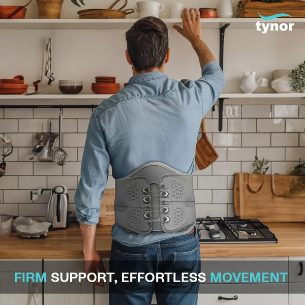 Man wearing a back brace in a kitchen with Tynor branding.